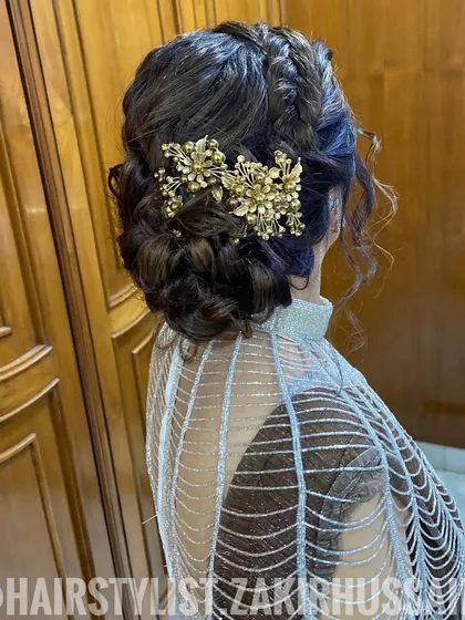 For this party look, I designed a braided updo and accessorized it with a large, ornate gold hairpiece. The style is both regal and modern, perfect for making a statement at a reception or sangeet.