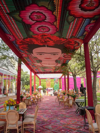 A view down the long corridor with the Frida Kahlo ceiling, showing the dining tables set for guests.
