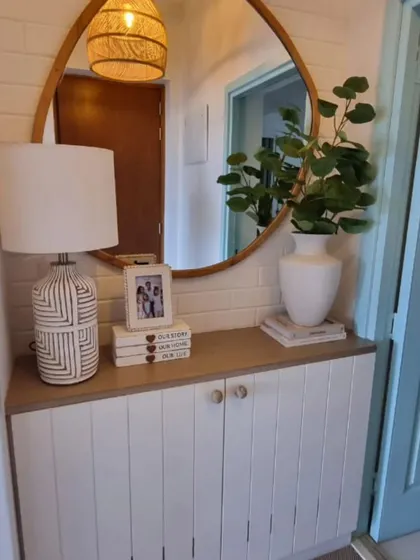 Your home’s first impression = nailed it. This minimalist entryway balances clean lines, warm wood accents, and a touch of green.