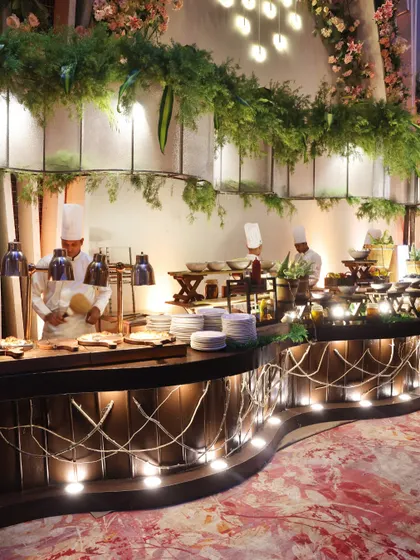 A wide view of our live cooking stations, beautifully integrated into the event decor with natural elements like wood and greenery. Our setups are designed to be both functional and aesthetically pleasing.