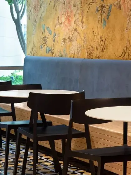 A cozy corner in an office cafeteria, featuring floral wallpaper and simple, modern furniture. This design shows how even small breakout areas can be transformed into pleasant and stylish spaces with the right material choices.