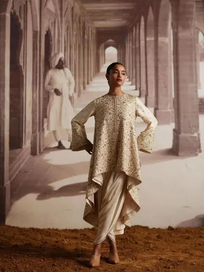 This look features an asymmetrical tunic with bell sleeves paired with dhoti pants. It's an example of fusion wear styling that is both contemporary and rooted in Indian silhouettes.
