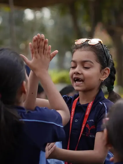 Two students playing a clapping game together during their break from farm activities.