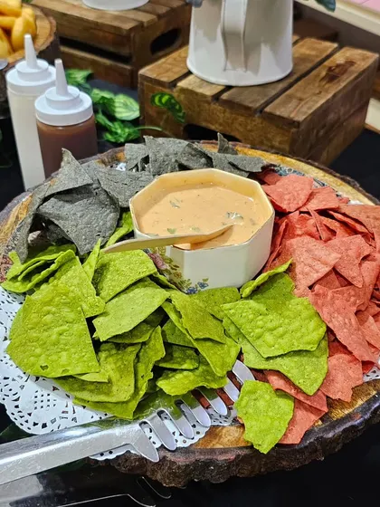A colorful platter of tri-color nachos served with a creamy cheese dip. This is a simple yet popular item that adds a fun crunch to any grazing table.