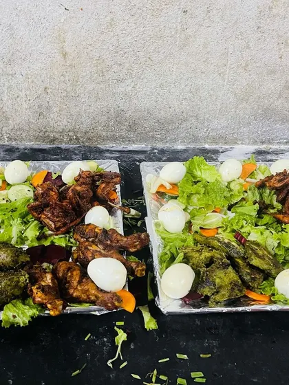 Two platters of our mixed starters ready for serving. Each platter is a mix of colors and flavors, with green hariyali chicken, red tandoori chicken, and boiled eggs on a bed of lettuce.