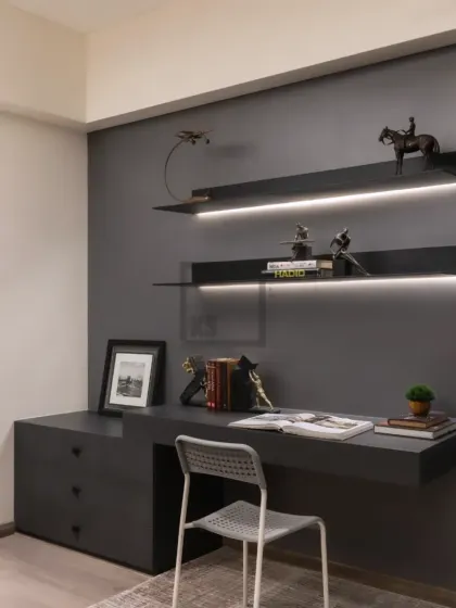 For those who need a dedicated workspace at home, I design custom study nooks. This setup features a floating desk with drawers and sleek, back-lit shelves against a dark grey accent wall for a focused environment.