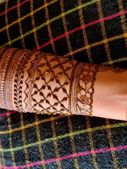 A close-up of the armband portion of a Seemantham henna design, showing a neat geometric pattern.
