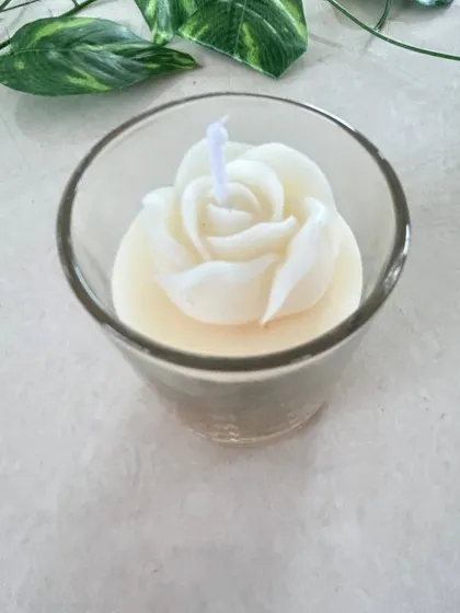 A simple and elegant white rose candle in a glass holder.