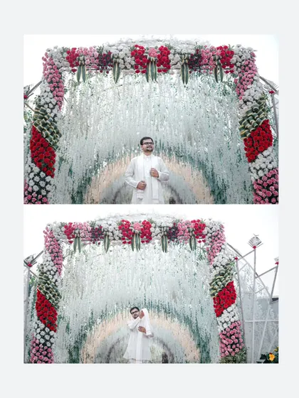 The groom stands under a magnificent floral archway, a stunning portrait that highlights the grand scale of the wedding decor.