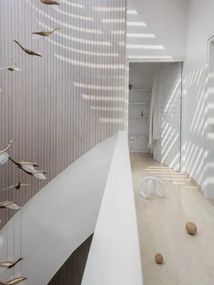Fluid forms in white and wood are bathed in natural light from strategically placed skylights, which create an evolving interplay of light and shadow throughout the day.