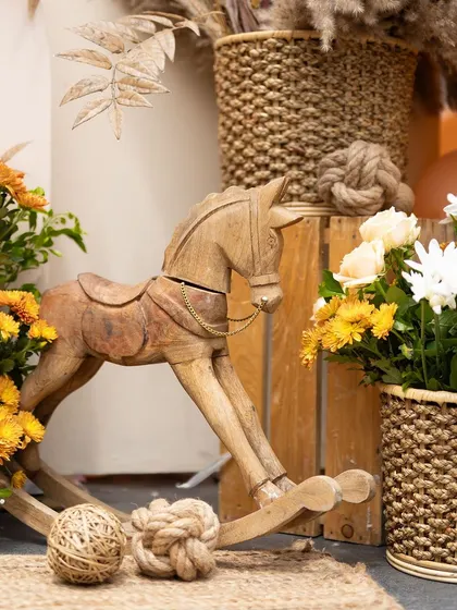 A close-up of a wooden rocking horse, a classic and charming decor element for a boho or rustic-themed baby shower.