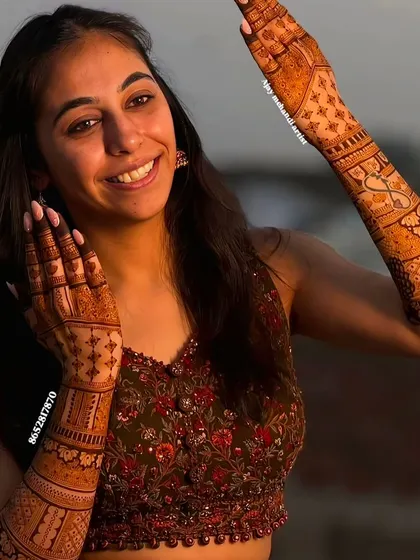 A happy, smiling client showing off her full-arm mehndi outdoors.