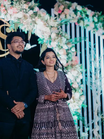 A candid moment of the couple enjoying their celebration in front of a modern, white-paneled backdrop with floral accents.