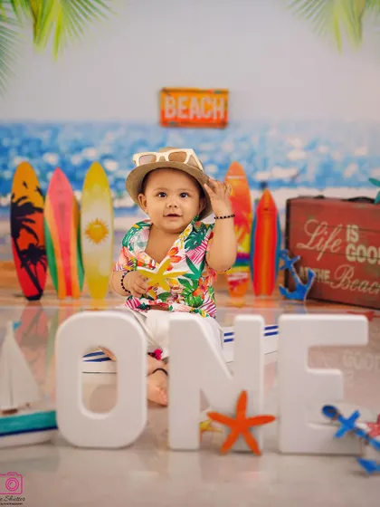 A fun, beach-themed first birthday shoot. This little guy is ready for summer, sitting with his "ONE" sign and a surfboard backdrop.