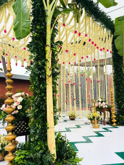 A close-up of our eco-friendly mandap, showing the detail of the jasmine flower curtain, the lush green pillars, and the traditional brass lamp.