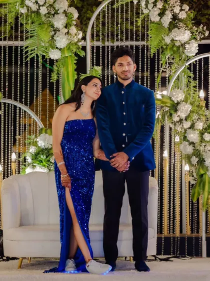 A full-length view of the couple against the modern reception backdrop. The design, featuring clean lines, sparkling crystals, and lush greenery, provides a perfect setting for stylish evening events.