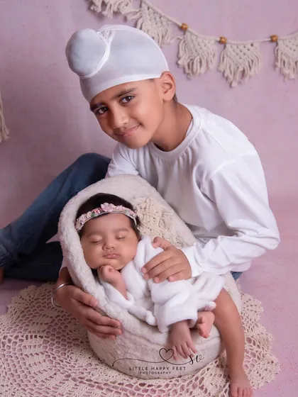 A proud Sikh boy holding his newborn baby sister. This portrait is a beautiful blend of sibling love and cultural pride.