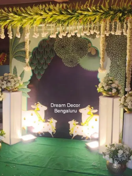 This Pichwai decor uses a darker, more subtle color palette, which looks incredibly elegant. The cow motifs and white floral arrangements create a serene and sophisticated atmosphere.