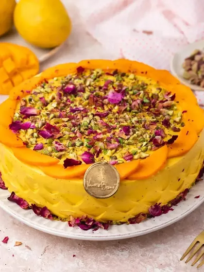 This is our Mango Pistachio Rose Cake, an elegant twist on a classic. We blend fresh mango pulp into the cream, then top it with sliced mangoes, crushed pistachios, and edible rose petals for a truly gourmet experience.
