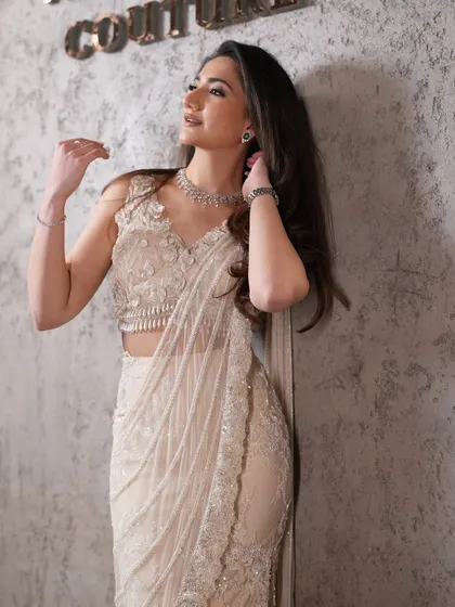 An exquisite ivory pre-draped sari with delicate embellishments and a high slit, blending traditional elegance with modern grace for a refined yet contemporary look.