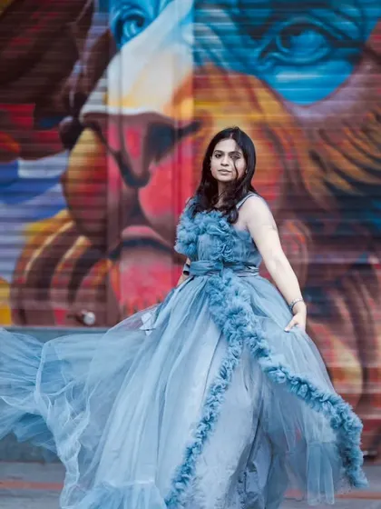 This shot shows the grey frill gown in motion against a colorful mural, highlighting its versatility for urban and artistic photoshoots.