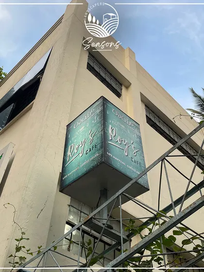 The sign for Roy's Cafe, one of our ongoing projects. This image marks the beginning of a transformation, where we will bring nature's beauty to life in their outdoor space.
