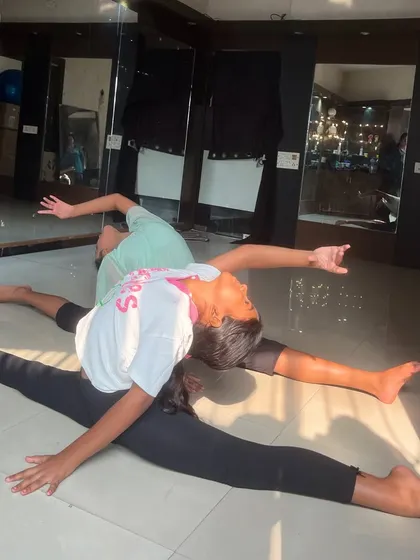 Two students practice a synchronized split on the floor, showcasing their flexibility and coordination. Partner work is an important part of my group classes.