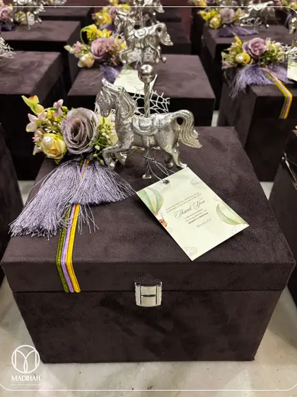 A close-up of a royal-themed baby announcement hamper, presented in a luxurious deep purple velvet chest. The gift is adorned with a silver-plated horse figurine and a custom 'Thank You' tag, making it a grand and memorable keepsake.