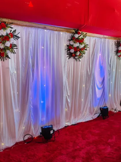 A simple backdrop of white drapes with fairy lights and blue uplighting. This can be used to cover a plain wall or create a photo corner for a birthday party.