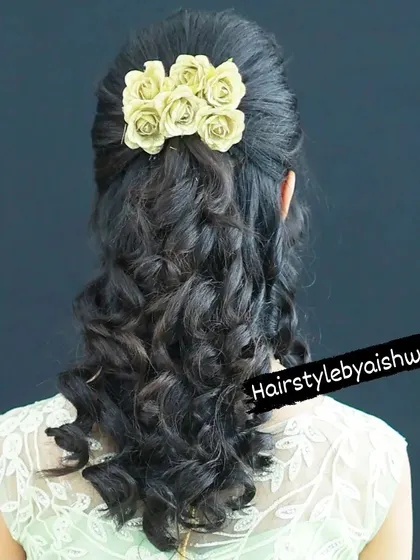 A simple and elegant half-up hairstyle with soft curls. The look is completed with a cluster of delicate paper roses for a romantic touch.