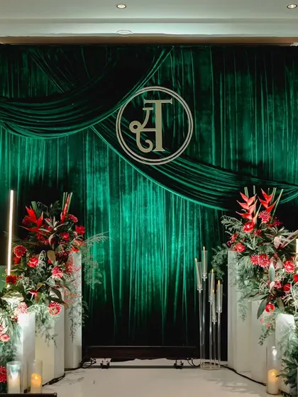 It's the personal touches that make a wedding truly yours. For this modern luxe reception, I created a dramatic photo backdrop with rich emerald velvet, accented by bold red tropical flowers and the couple's custom monogram.