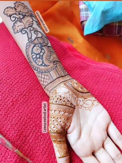 An in-progress shot of a heavy siders or party-wear design. This style features a dense pattern on the back of the hand and arm, often with peacock and floral elements.