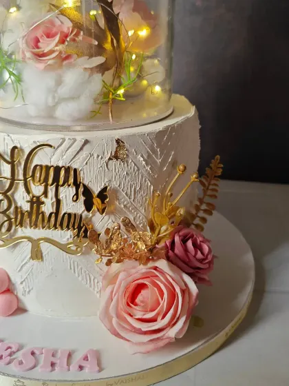 A close-up of the beautiful details on the 10th birthday cake, showing the intricate textures, gold butterflies, and fresh roses.