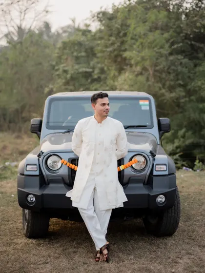 A stylish portrait of the groom-to-be leaning against a Mahindra Thar, combining a rustic feel with modern style.