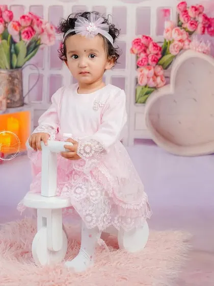 Standing confidently with her tricycle, this portrait captures a big step in her journey of milestones.