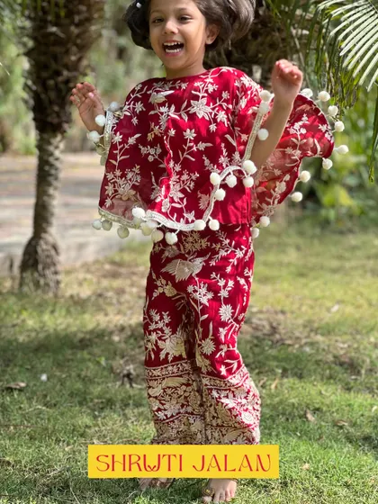 A candid shot of a little girl in my maroon floral co-ord set with a pom-pom cape. Her joyful expression is exactly why I focus on making my clothes comfortable enough for kids to be themselves.
