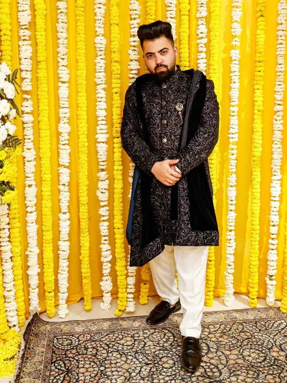 For your friend's wedding, make sure you shine. This groom's friend wears a regal black sherwani with a velvet stole, a customized designer piece that stands out.