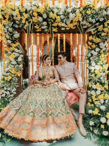 A beautiful portrait of the couple seated on a swing decorated with marigolds.