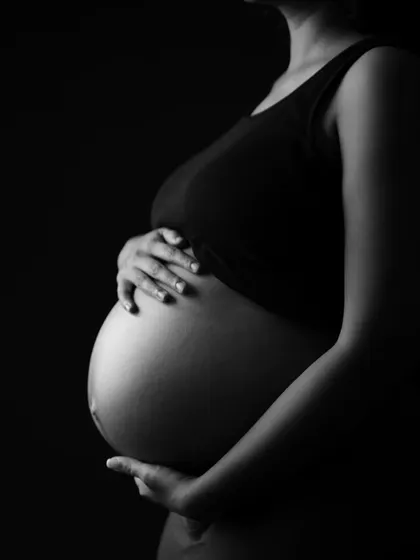 A close-up, artistic shot of the baby bump in black and white. The lighting beautifully highlights the shape and texture, celebrating the miracle of creating life.