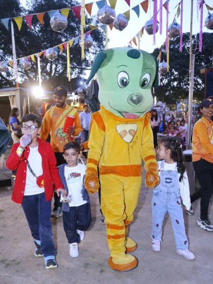 Tinga Dojo leads the way for an outdoor adventure, walking with a group of excited children through the festive grounds at Punjabi Bagh.