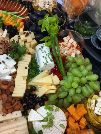 A close-up of a gourmet cheese platter, showcasing a wide selection of cheeses like feta, brie, and cheddar. It is garnished with fresh grapes, nuts, and olives, perfect for a wine and cheese evening.