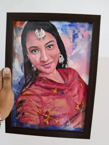 A framed oil portrait of a woman in traditional Punjabi attire. The abstract background complements the vibrant colors of her dress.