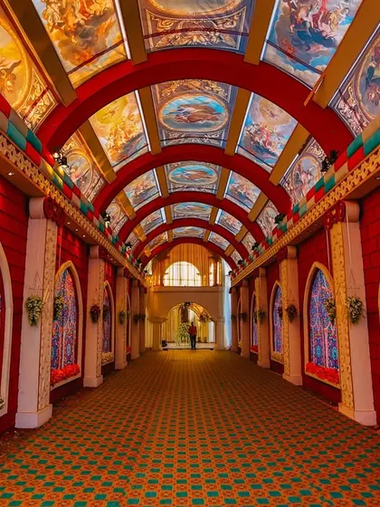 An incredibly detailed and artistic wedding entrance. The arched hallway features stained-glass style windows and a ceiling painted with Renaissance-style art, creating a truly unique and breathtaking experience.