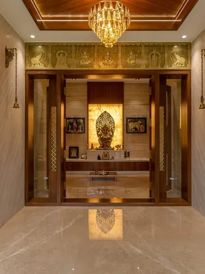We design serene and spiritually uplifting pooja rooms. This space features ornate brass bells, a traditional carved backdrop, and elegant marble flooring, creating a dedicated space for meditation and worship.