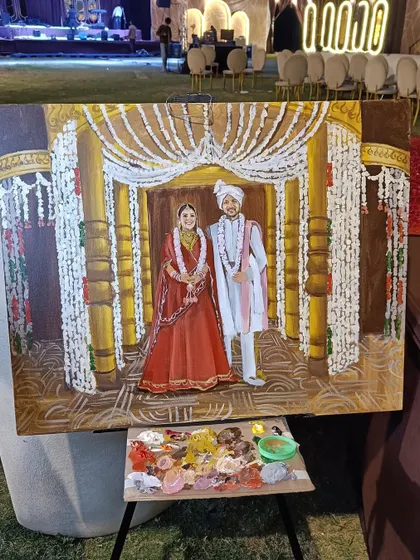 The painting in progress at the Raipur wedding venue. This shot shows the scale of the canvas against the magnificent, brightly lit stage.