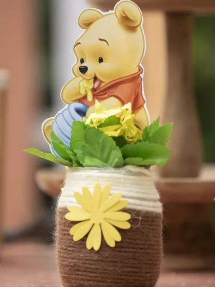 A close-up of a 'Winnie the Pooh' centerpiece. The small Pooh cutout and the twine-wrapped jar add a rustic, charming feel to the table.