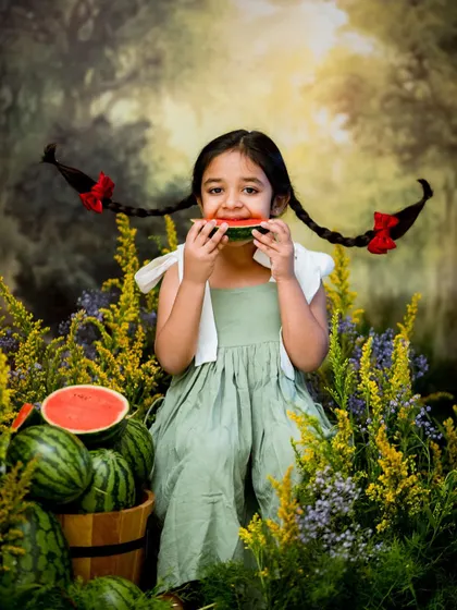 Enjoying a slice of watermelon in a field of flowers. Seasonal concepts like this are a fun way to create unique and timely portraits.
