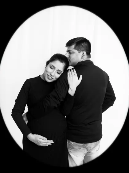 A tender black and white shot capturing a quiet moment of affection. The oval framing adds a vintage, intimate touch.