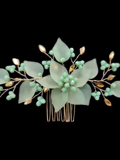 A beautiful hair comb featuring soft, mint-green translucent flowers and leaves with golden accents. This piece is perfect for a modern, ethereal bridal look.