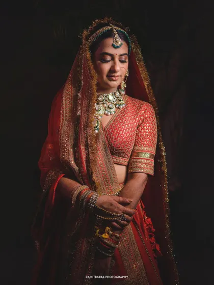 A dramatic, low-key portrait of the bride in her red lehenga, creating a timeless and artistic look.